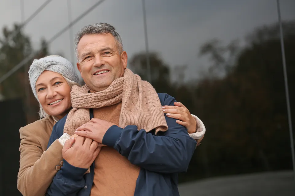 A smiling older couple standing close together outdoors